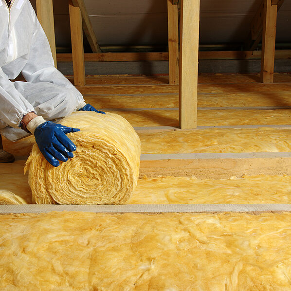 House attic insulation - construction worker installing glass wool