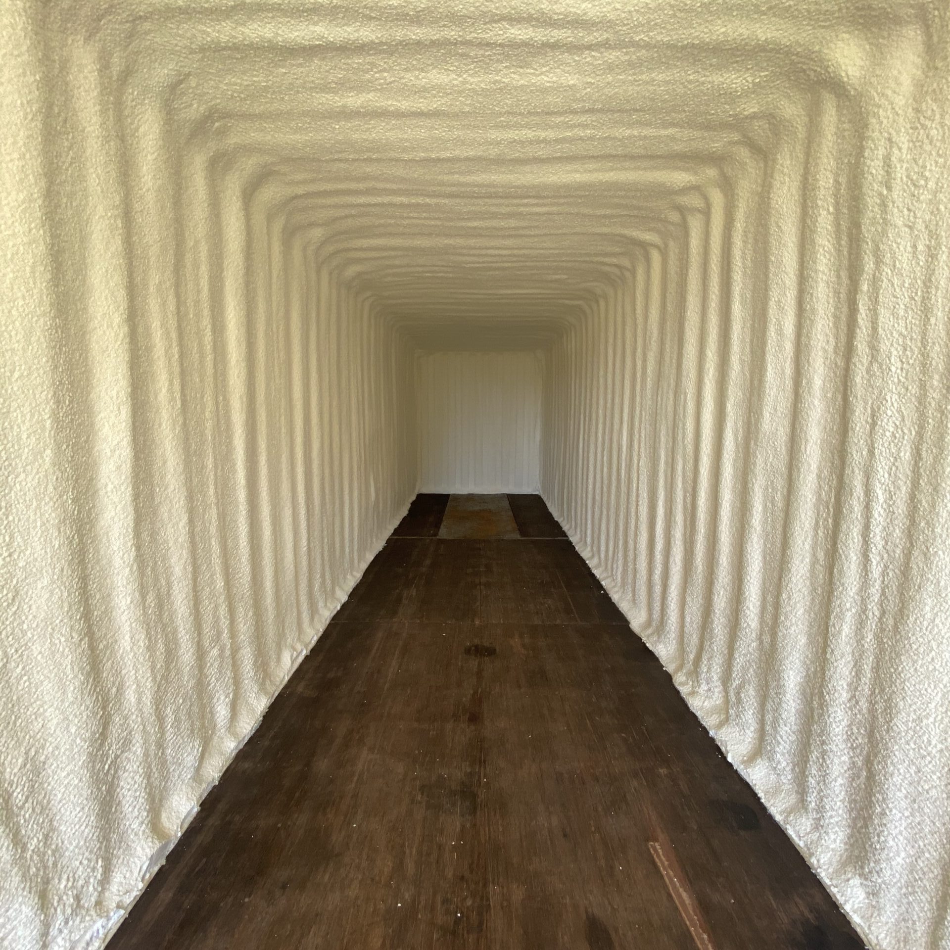 a long narrow hallway with white walls and wood flooring